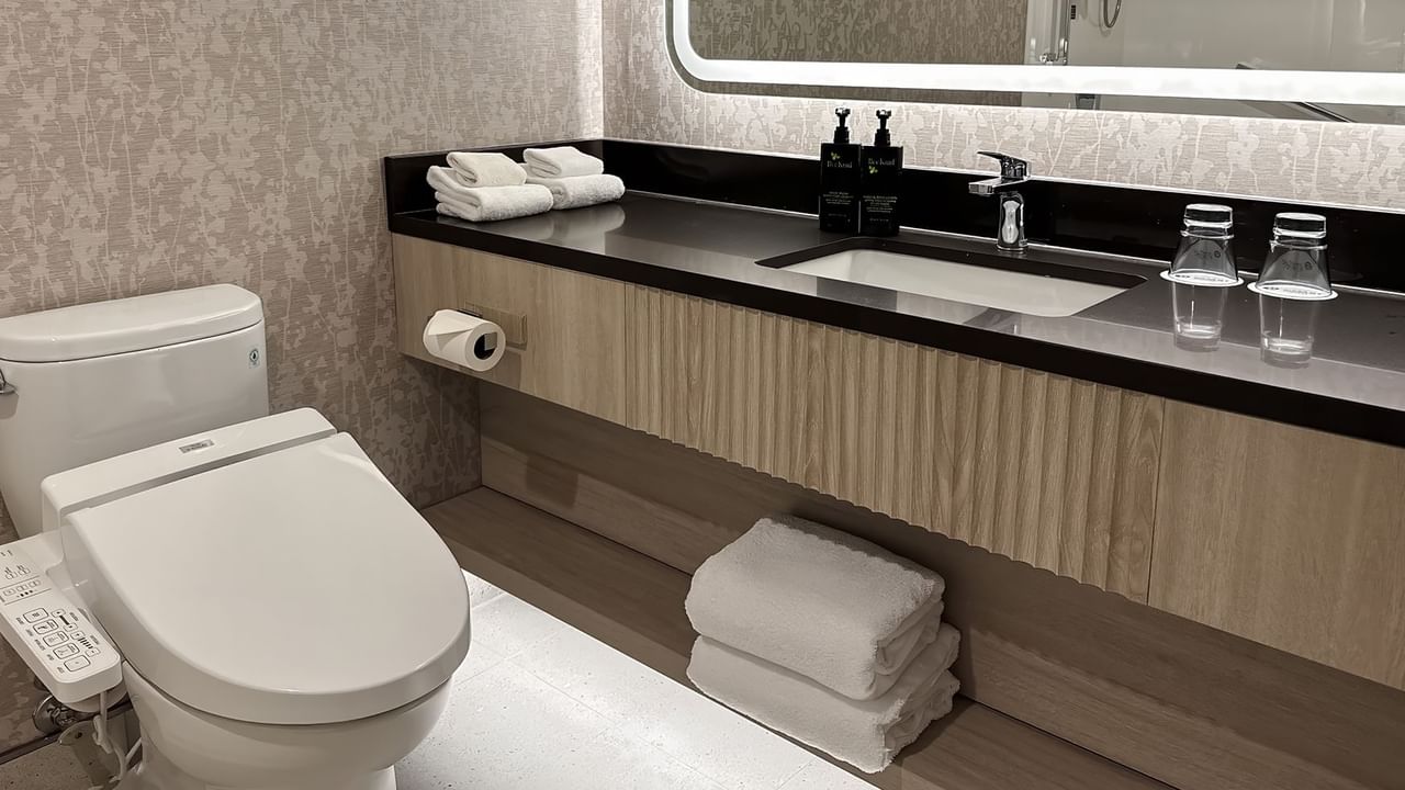 Hotel washroom with towels, sink, soap, and TOTO Washlet