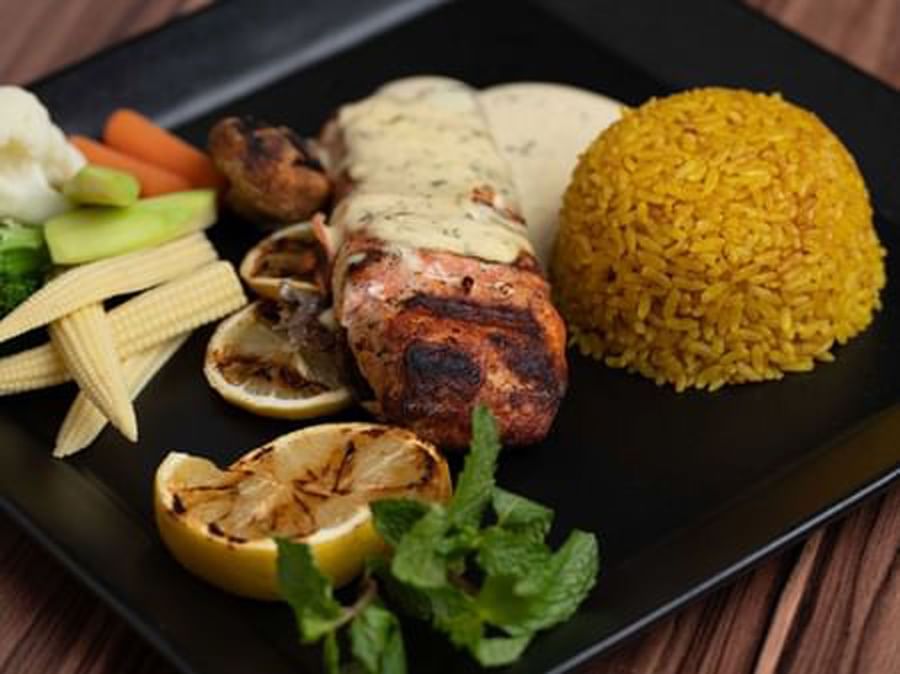 Grilled salmon with lemon slices by a dome of yellow rice and steamed vegetables at Warwick Al Jubail