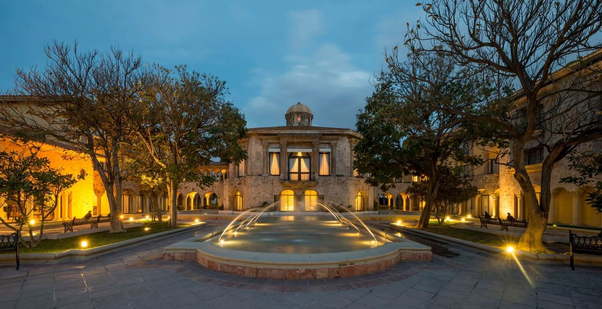 Illuminated courtyard fountain under a twilight sky at luxurious Quinta Real Aguascalientes