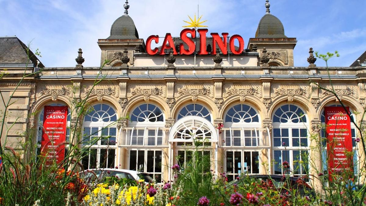Entrée d'un casino avec un extérieur architectural orné et des fleurs en avant-plan.