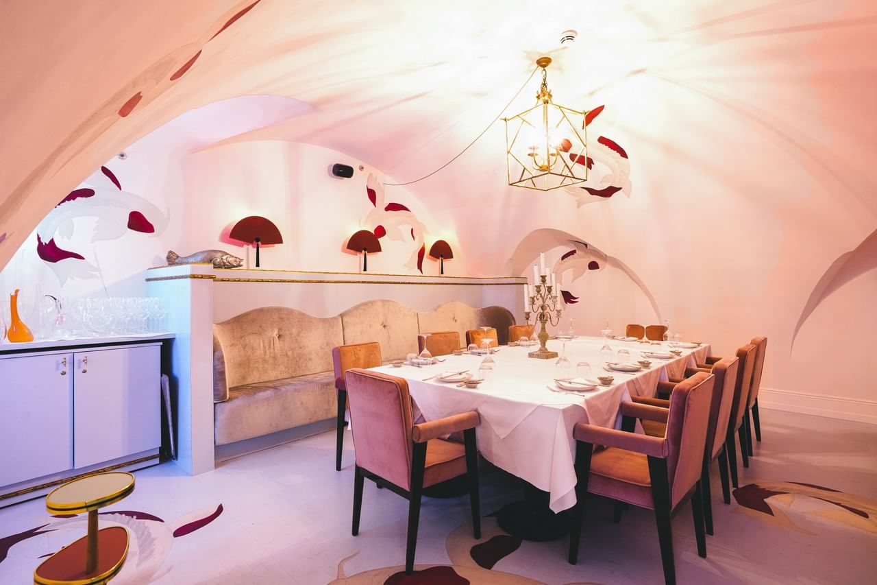 Salon Asiatique at Hotel THE LEO GRAND with an elegantly set table, pink velvet chairs, vaulted ceiling and Asian inspired wall art
