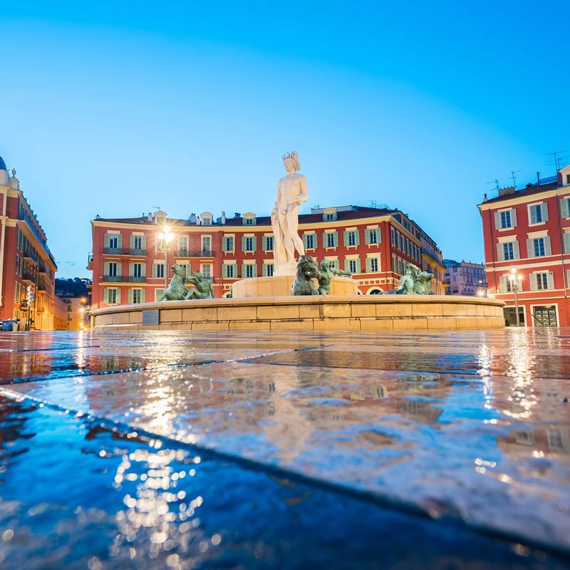 A scenic view of Nice square place, showcasing a prominent fountain surrounded by buildings near Warwick Hotels and Resorts