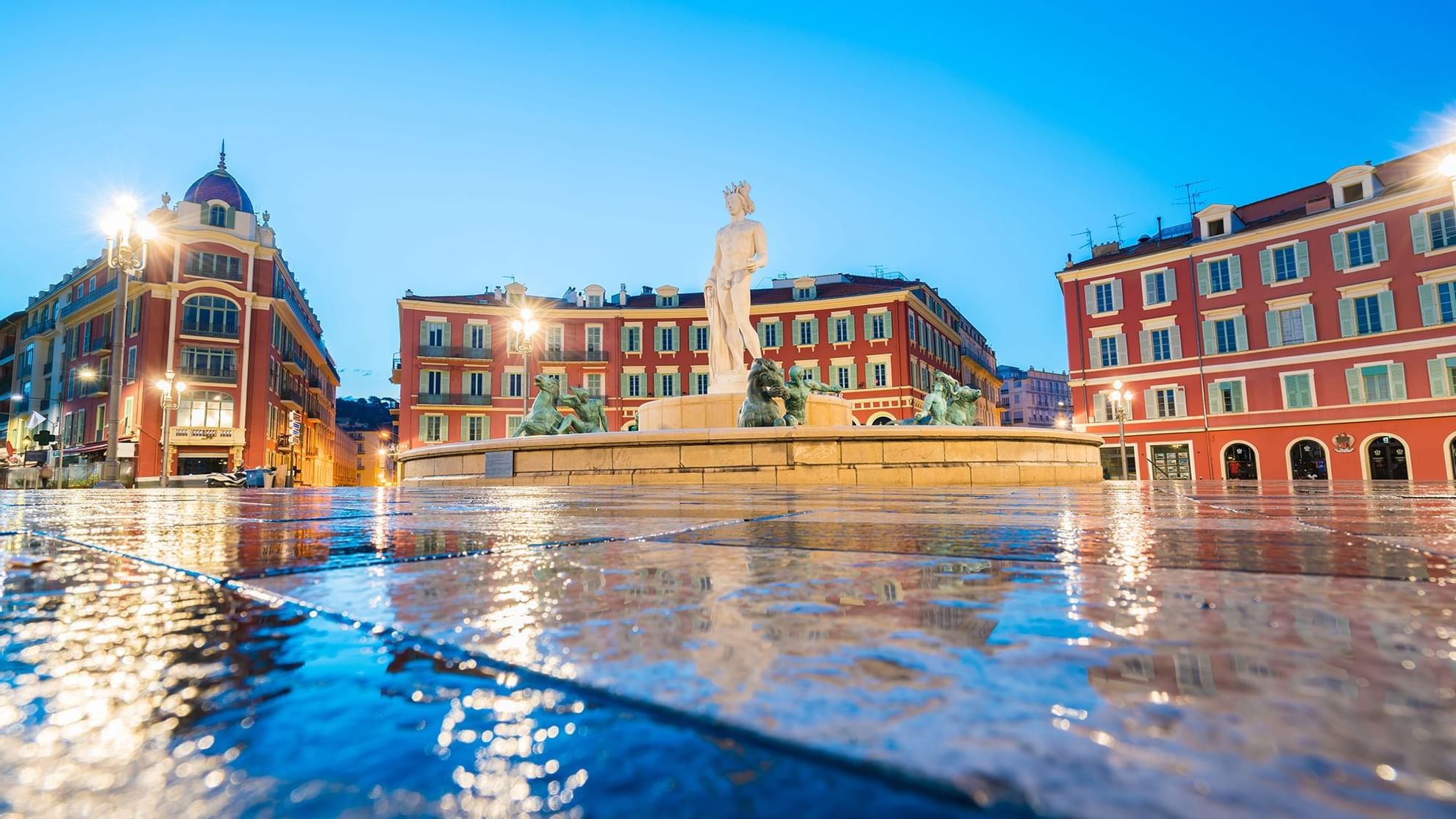 A scenic view of Nice square place, showcasing a prominent fountain surrounded by buildings near Warwick Hotels and Resorts