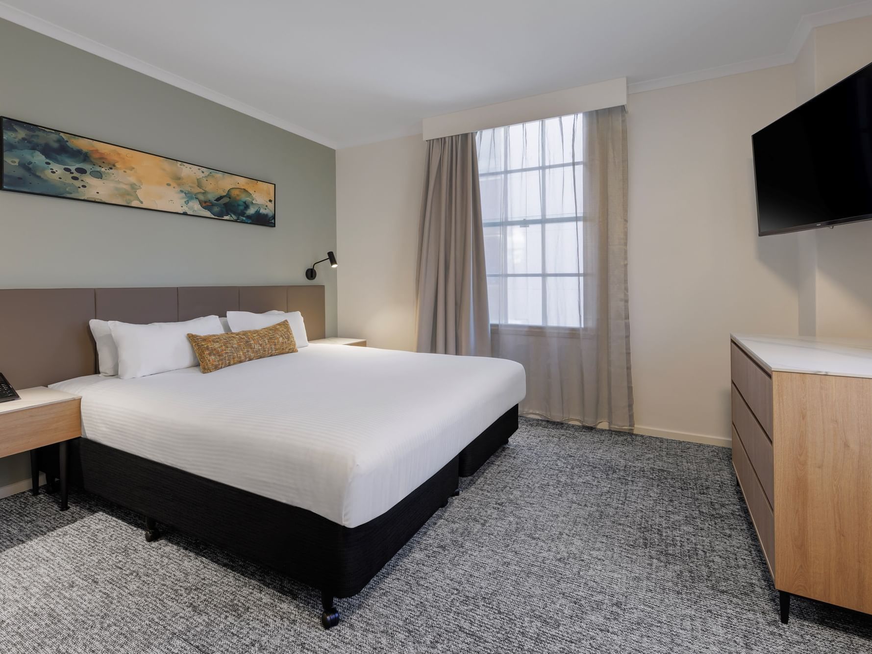 Large suite bed with a mounted TV and stylish decor.