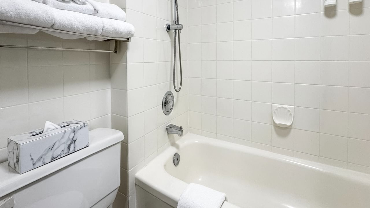 Coast King bathroom with bathtub, shower, towel rack, and toilet with tissue box at Coast Lonsdale Quay Hotel