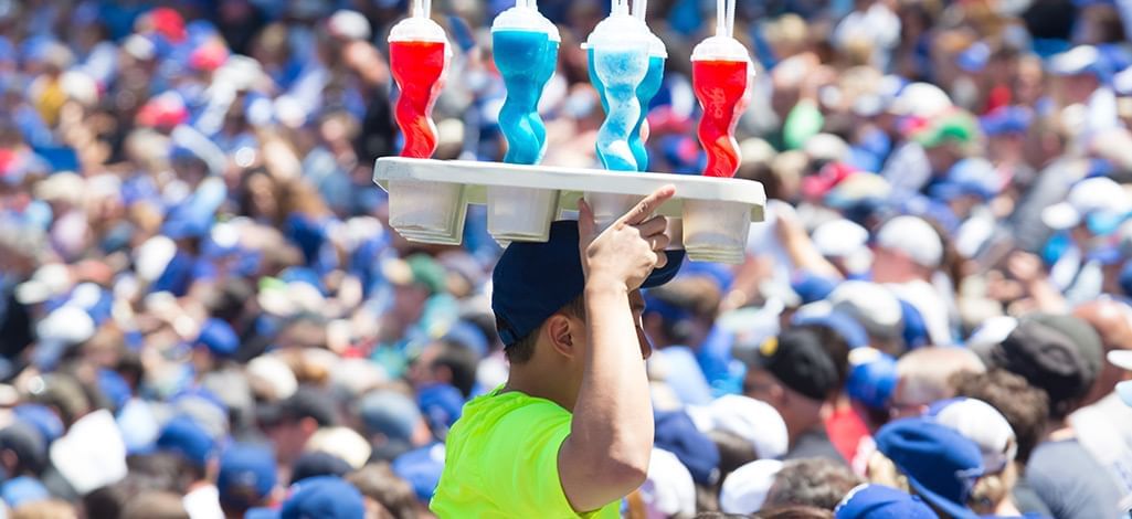 man carrying tray with drinks at a ball park