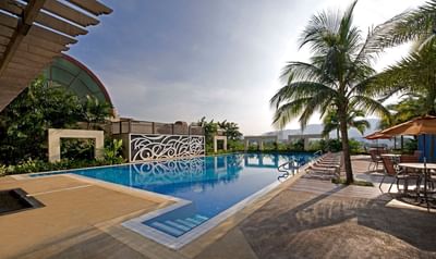 Landscape view of coconut trees & lounge chairs by the outdoor pool at One World Hotel