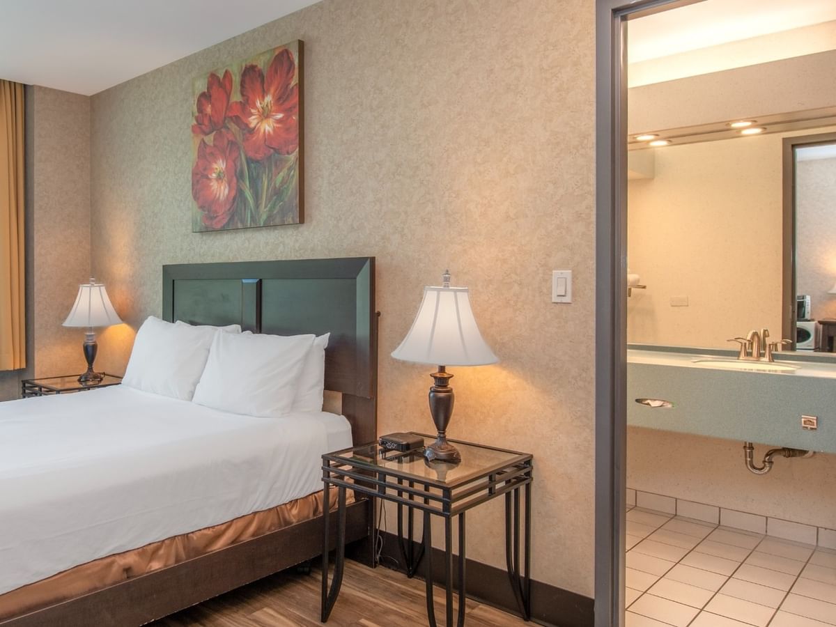 Coast Queen room with a bed, two nightstands with lamps, and a bathroom with a sink at Coast Lonsdale Quay Hotel