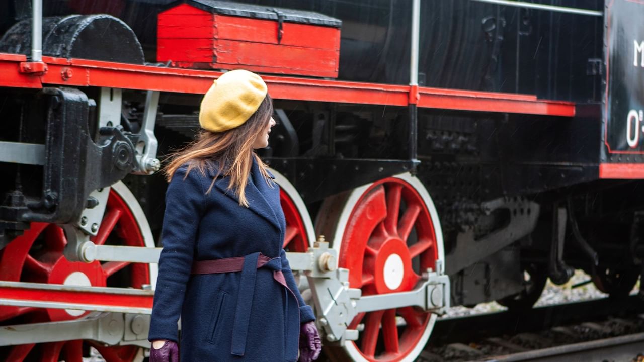 A woman stands in front of a train