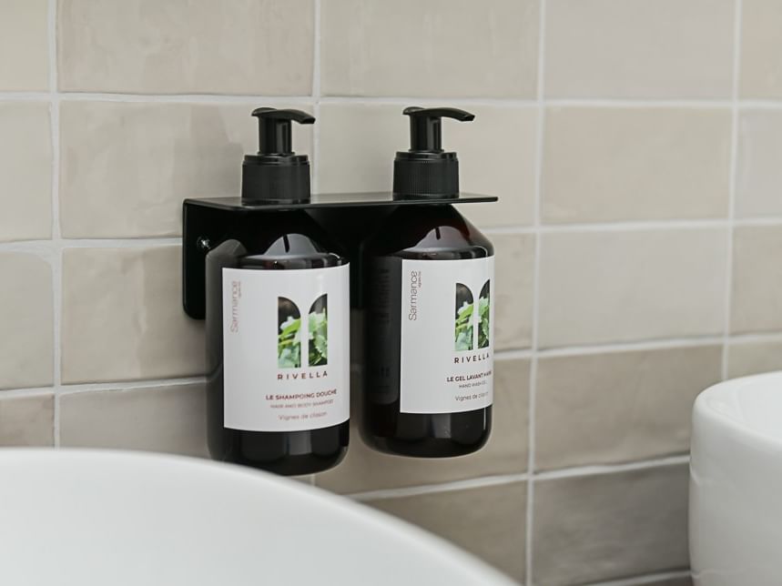 Deux flacons de shampoing et gel douche Rivella sur support mural