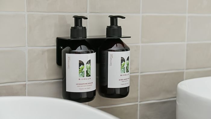 Deux flacons de shampoing et gel douche Rivella sur support mural