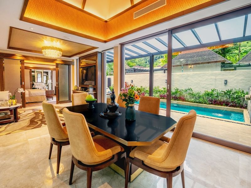 Luxurious dining area with a table, chairs, and a pool view through glass doors promoting ultra-luxury festive stay package