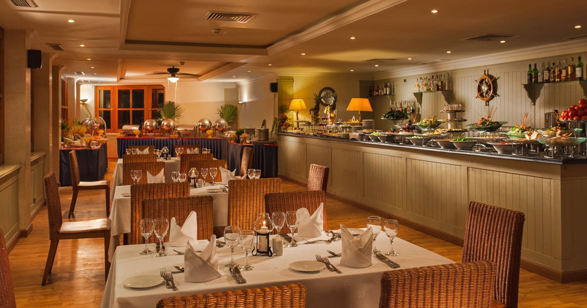 Elegant dining area of Wasabi at Pickalbatros Golf Beach Resort, with set tables and a buffet area, illumed by warm lighting