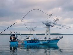 A man holds a net on a boat at Skins and Fins Fishing Charter near Bayside Inn Key Largo