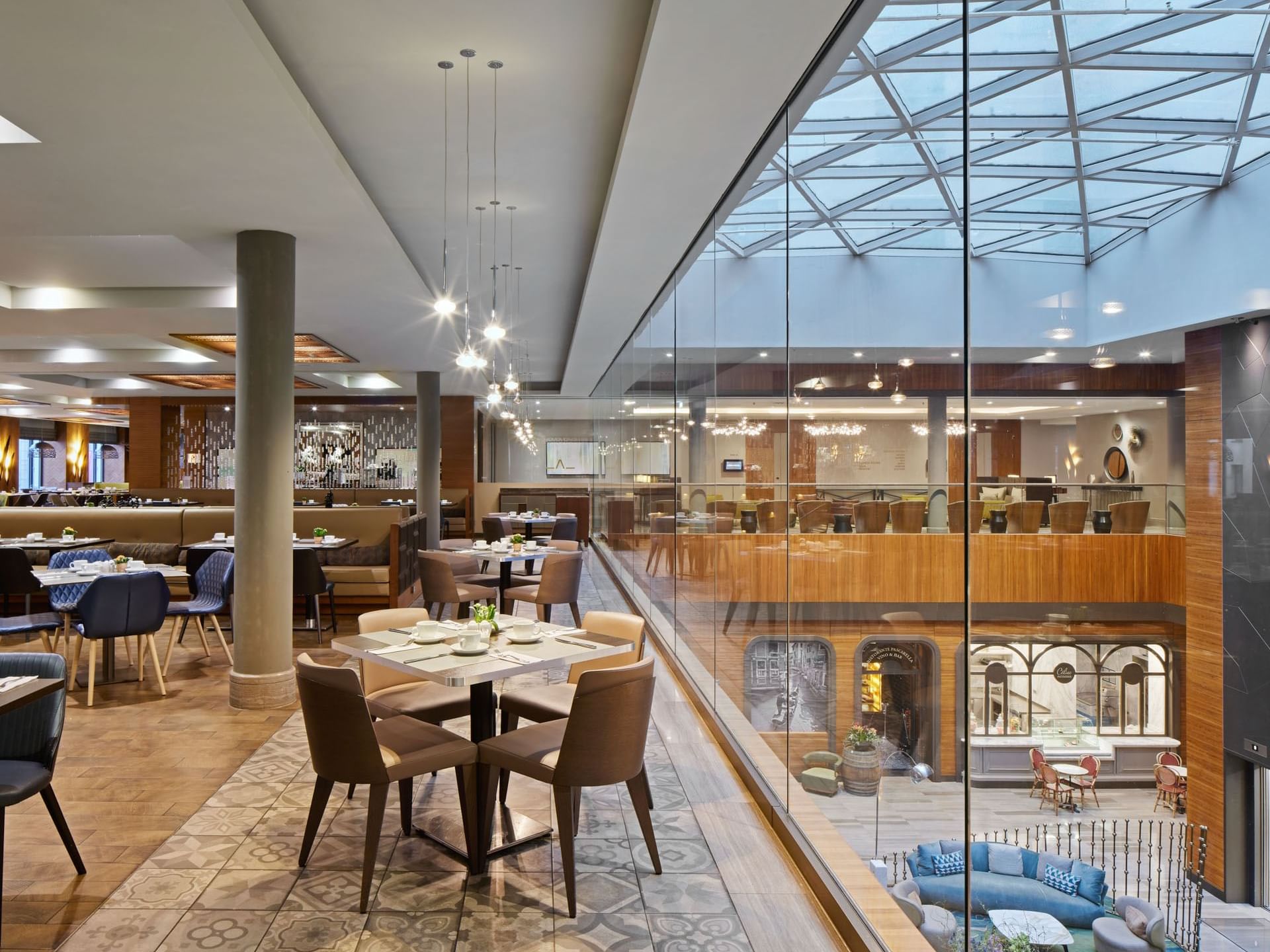 Modernes Restaurant mit Tischen, Stühlen und Glasfassade – Titanic Chaussee Berlin.