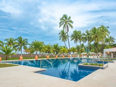 Outdoor pool with blue deck and palm trees at Best Western Jaco Beach