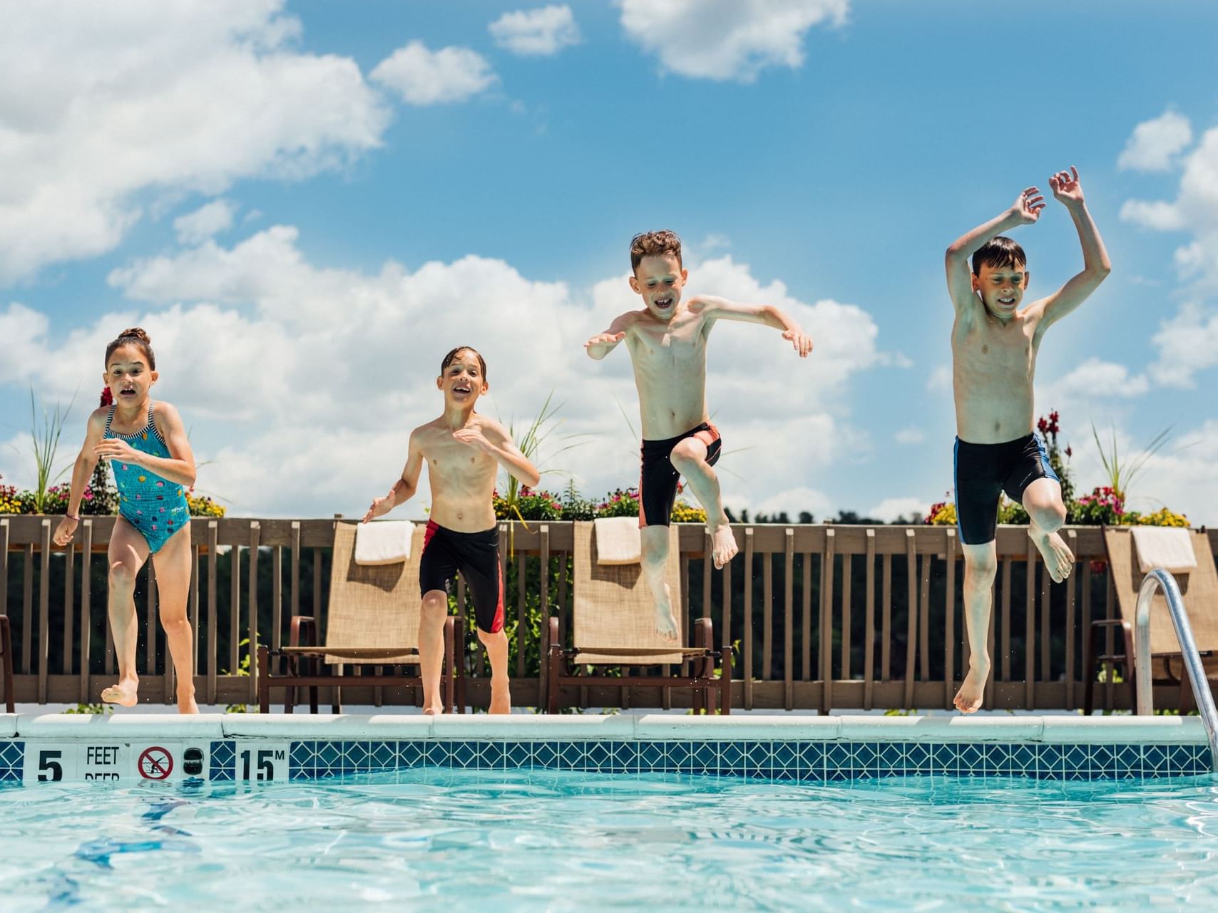 Four children jumping into the waterfront pool.