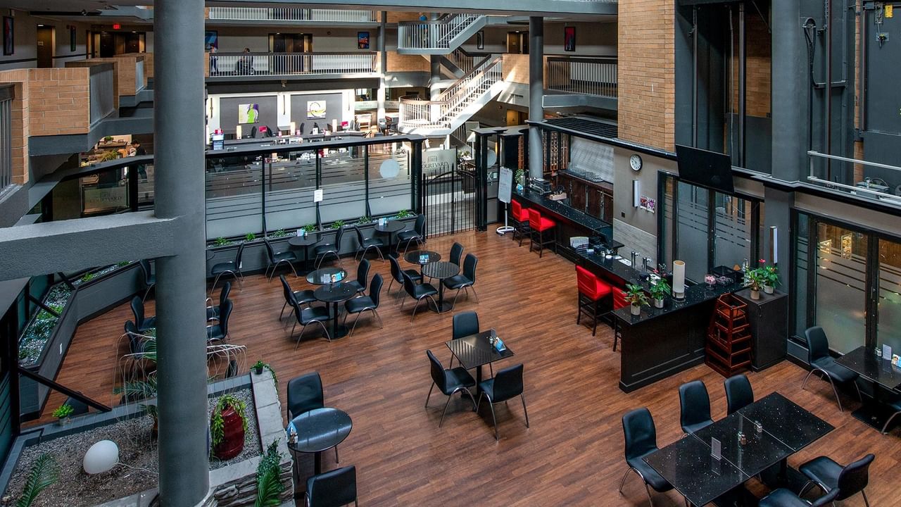 Multi-level atrium lobby with wood flooring, black seating areas, and modern architectural details at Coast Calgary University Area Hotel by APA