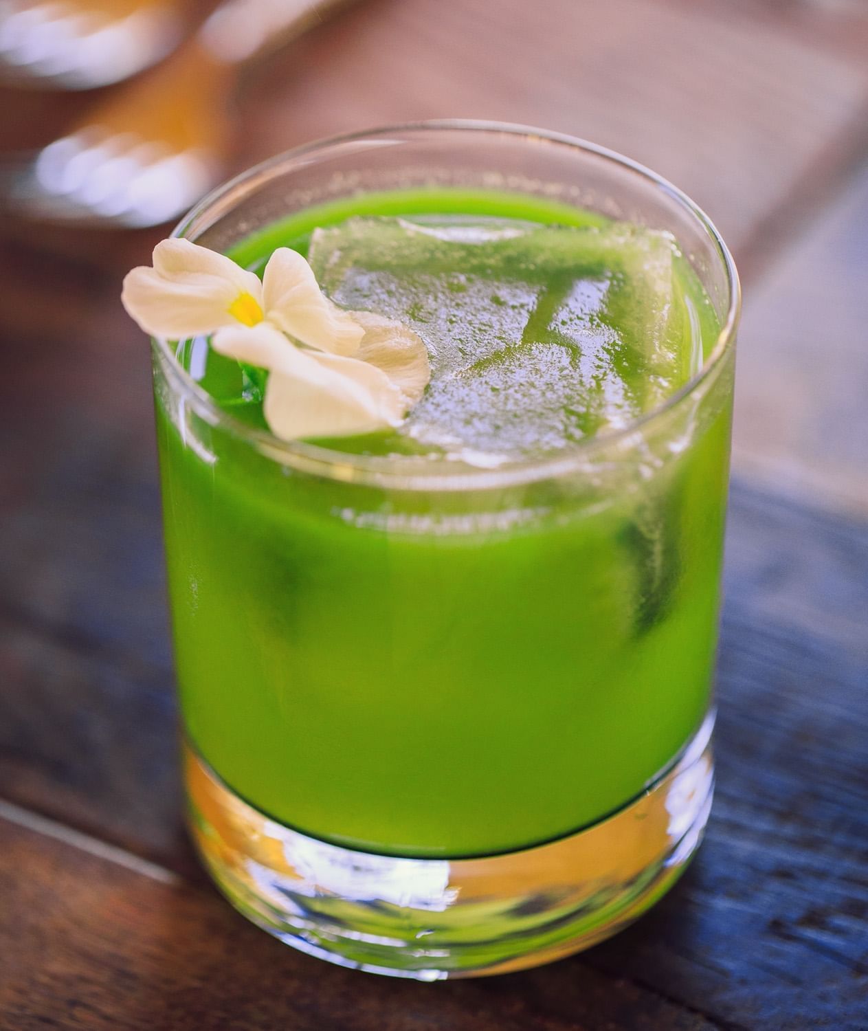 Lorem ipsum Cello's Green Ocean Cocktail garnished with a white flower.