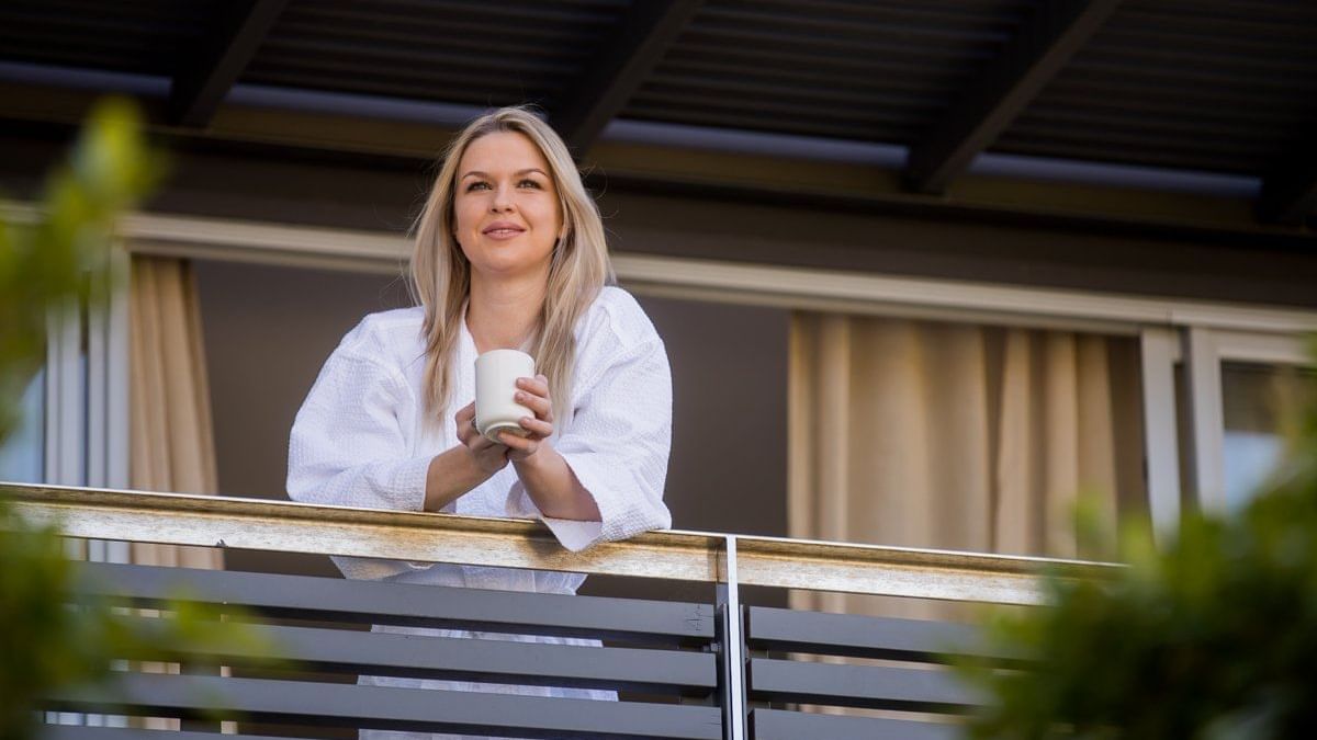 Lady standing with cup of water near the balcony at Pullman Magenta Shores