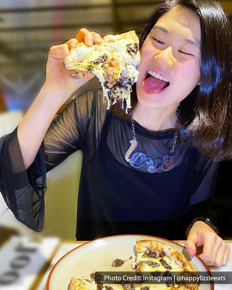 Lady enjoying a cheesy pizza served in a Restaurant near Imperial Lexis, best Malaysian Restaurants Kuala Lumpur