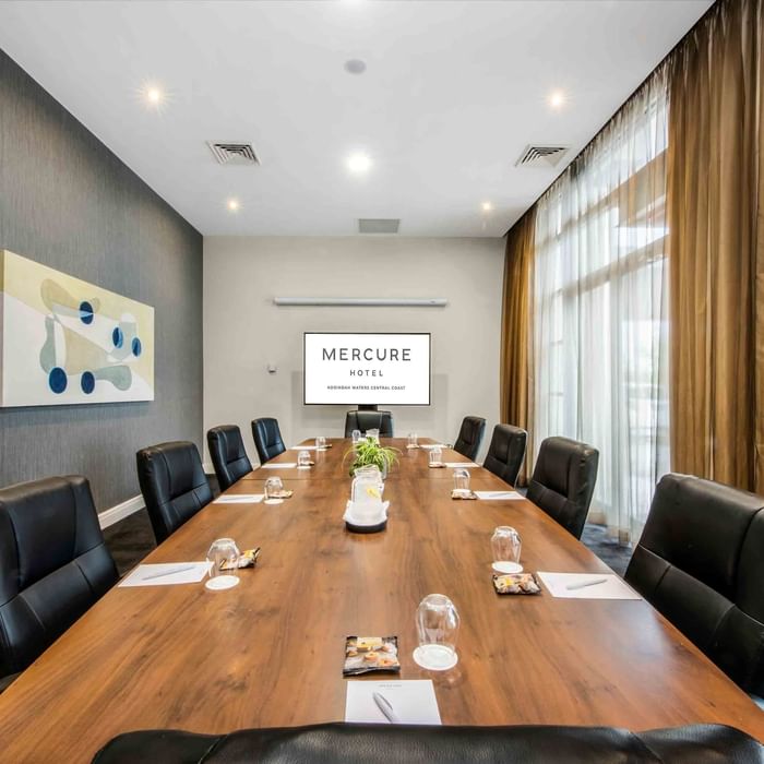 Boardroom One with a long table, black chairs, and abstract art on the wall at Mercure Kooindah Waters