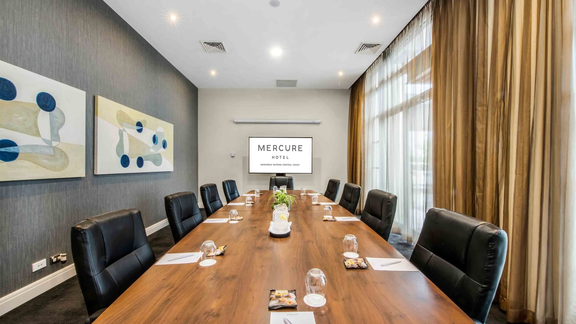 Boardroom One with a long table, black chairs, and abstract art on the wall at Mercure Kooindah Waters