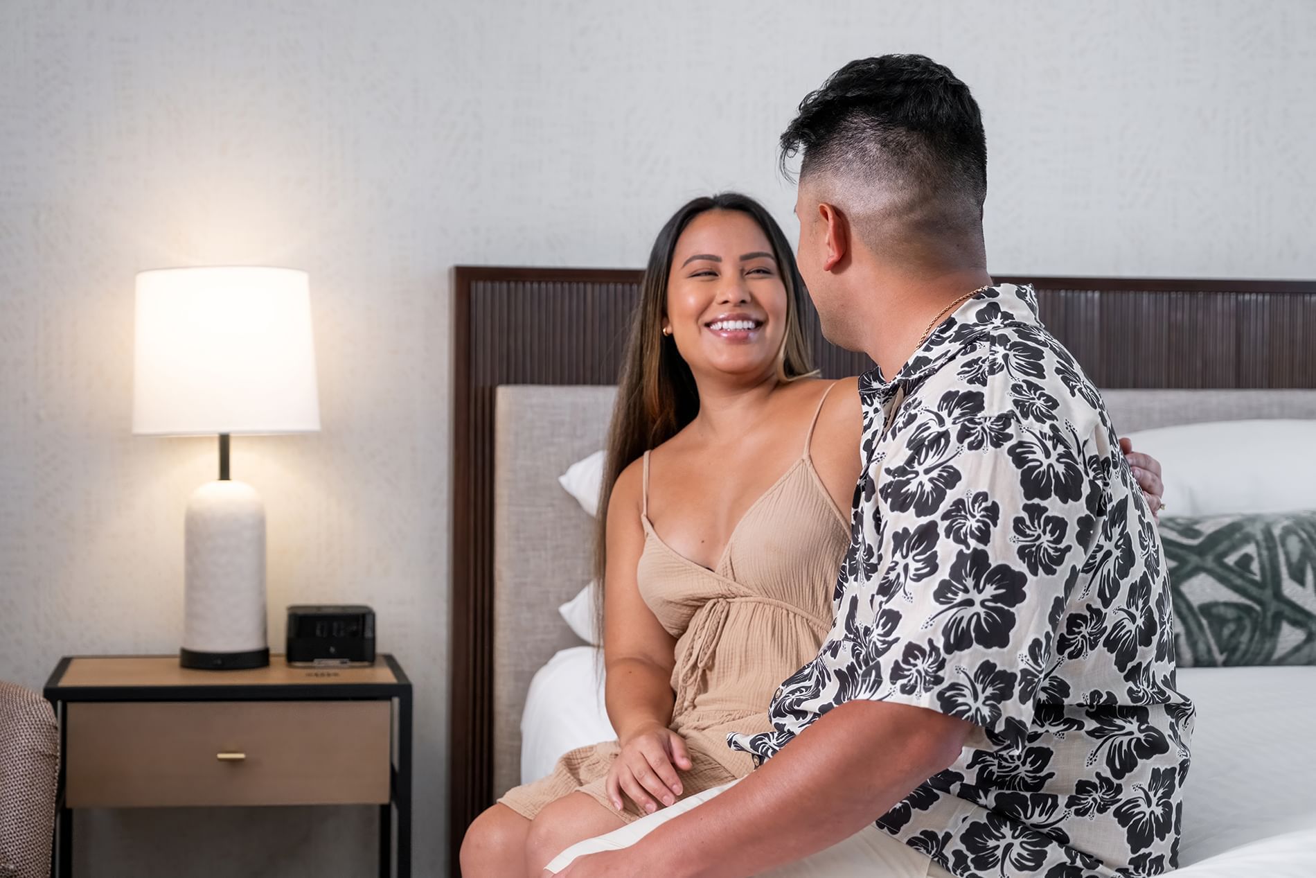 A couple is sitting on a bed in a hotel room.