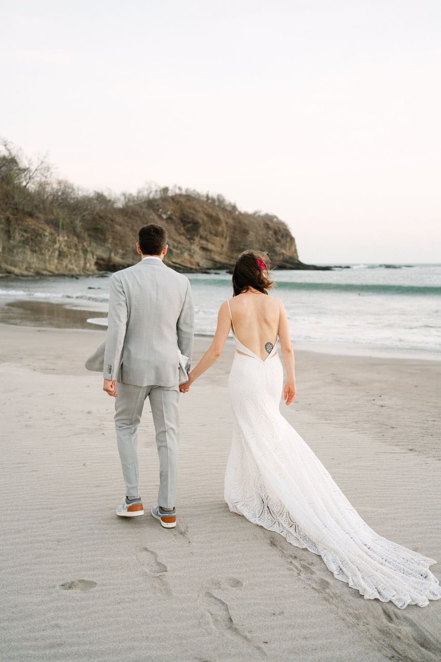 Couple walking by the ocean waves on a sandy beach at Morgan's Rock Reserve & Ecolodge