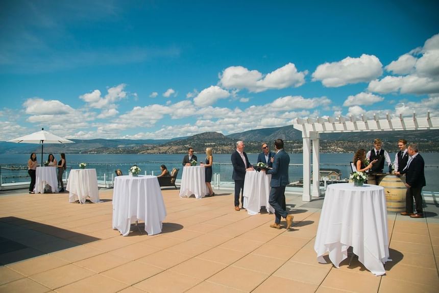 Outdoor terrace with standing cocktail tables and lake view.
