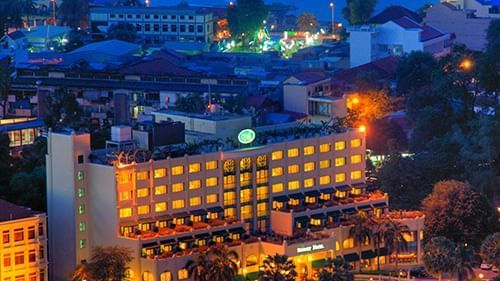 An evening exterior shot of Sunway Hotel Phnom Penh, brightly lit against the dark sky, surrounded by city lights