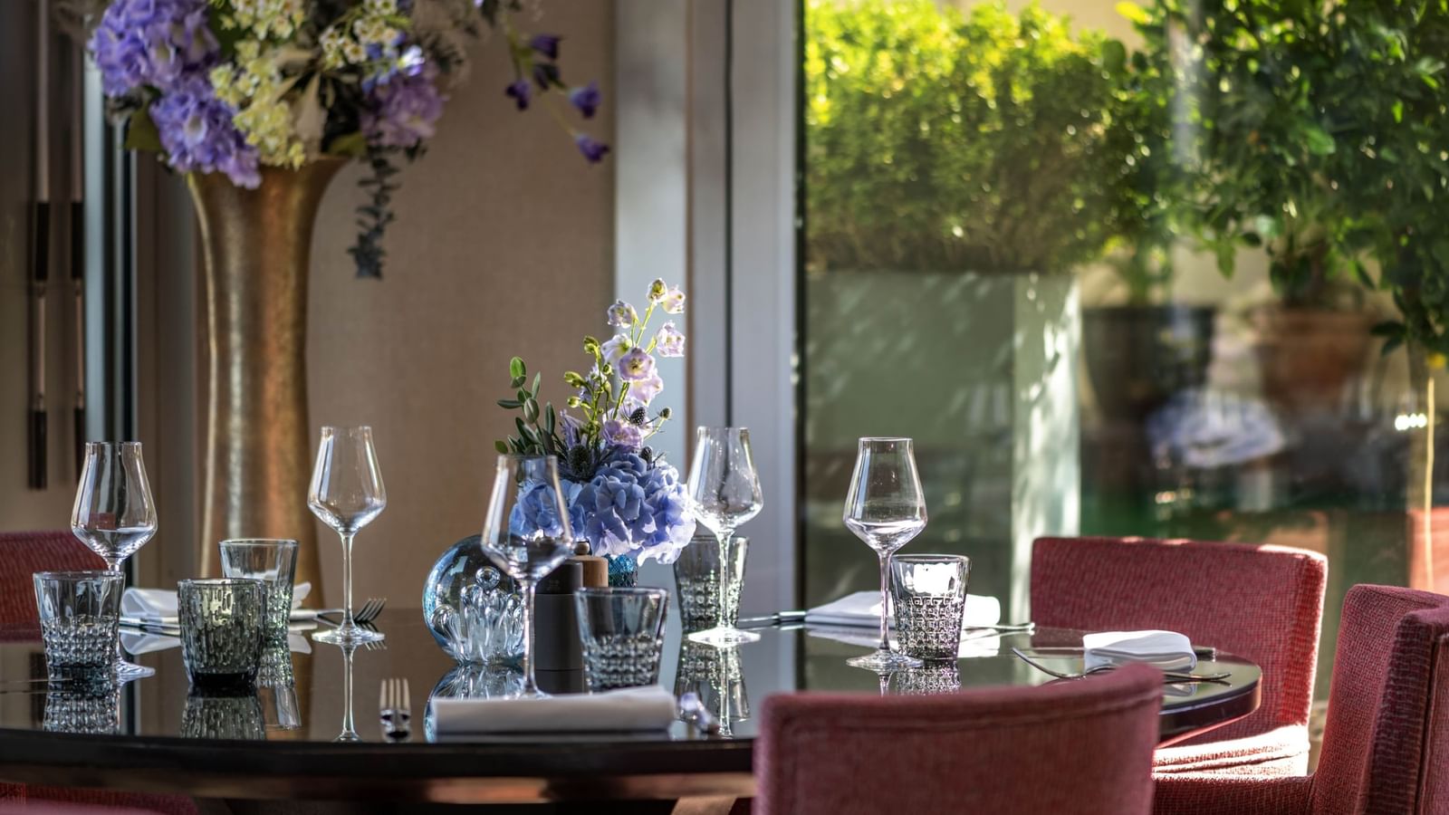Table dressée avec des verres à vin et des compositions florales à la Terrace Le W, au Warwick Champs-Élysées, à Paris.