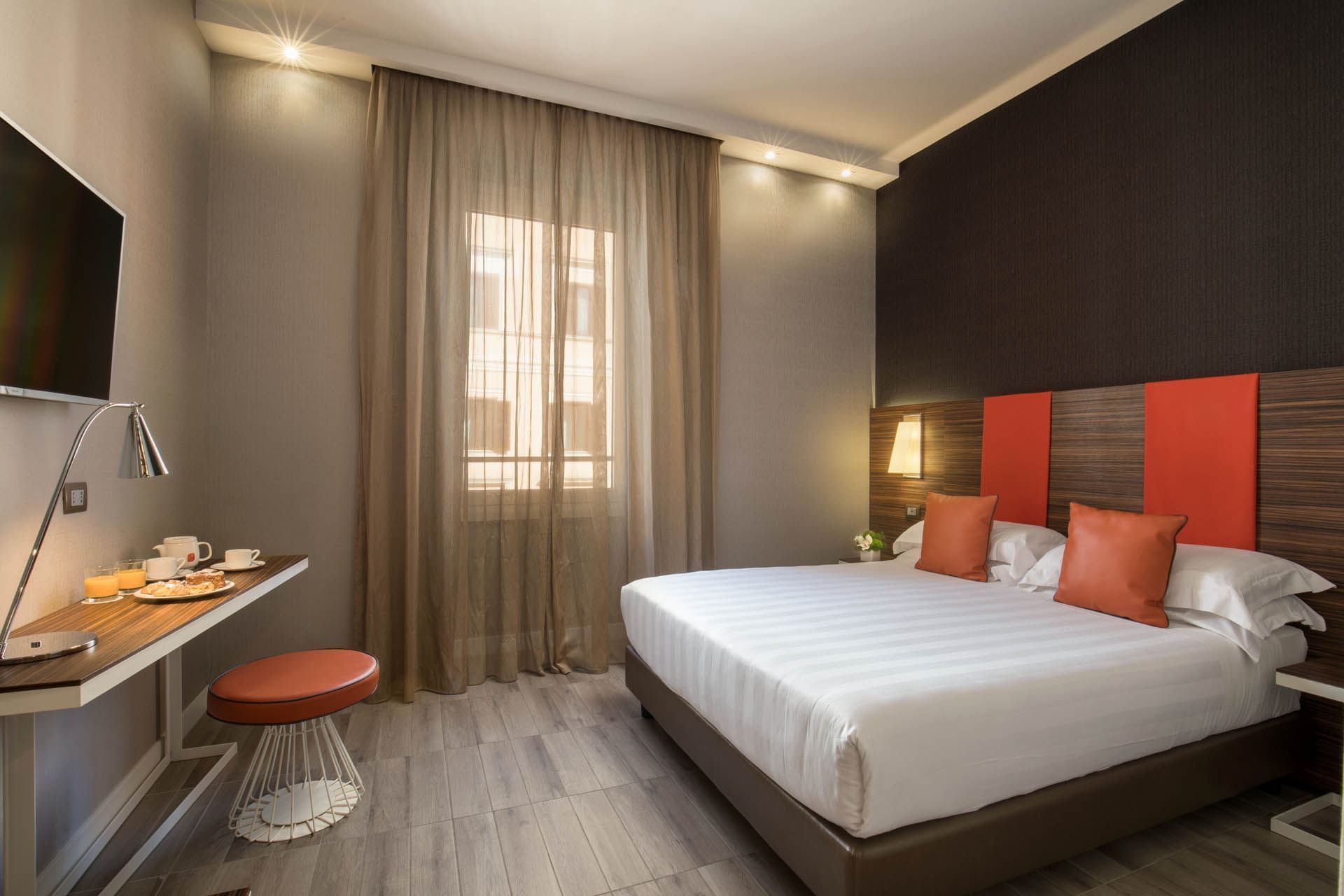 Classic room featuring a bed with orange cushions, wooden accents, a desk with breakfast at The Republic Hotel