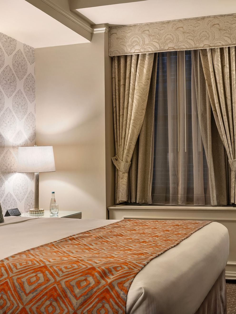 Bed with side table and couch near window in Premier Suite at Warwick New York