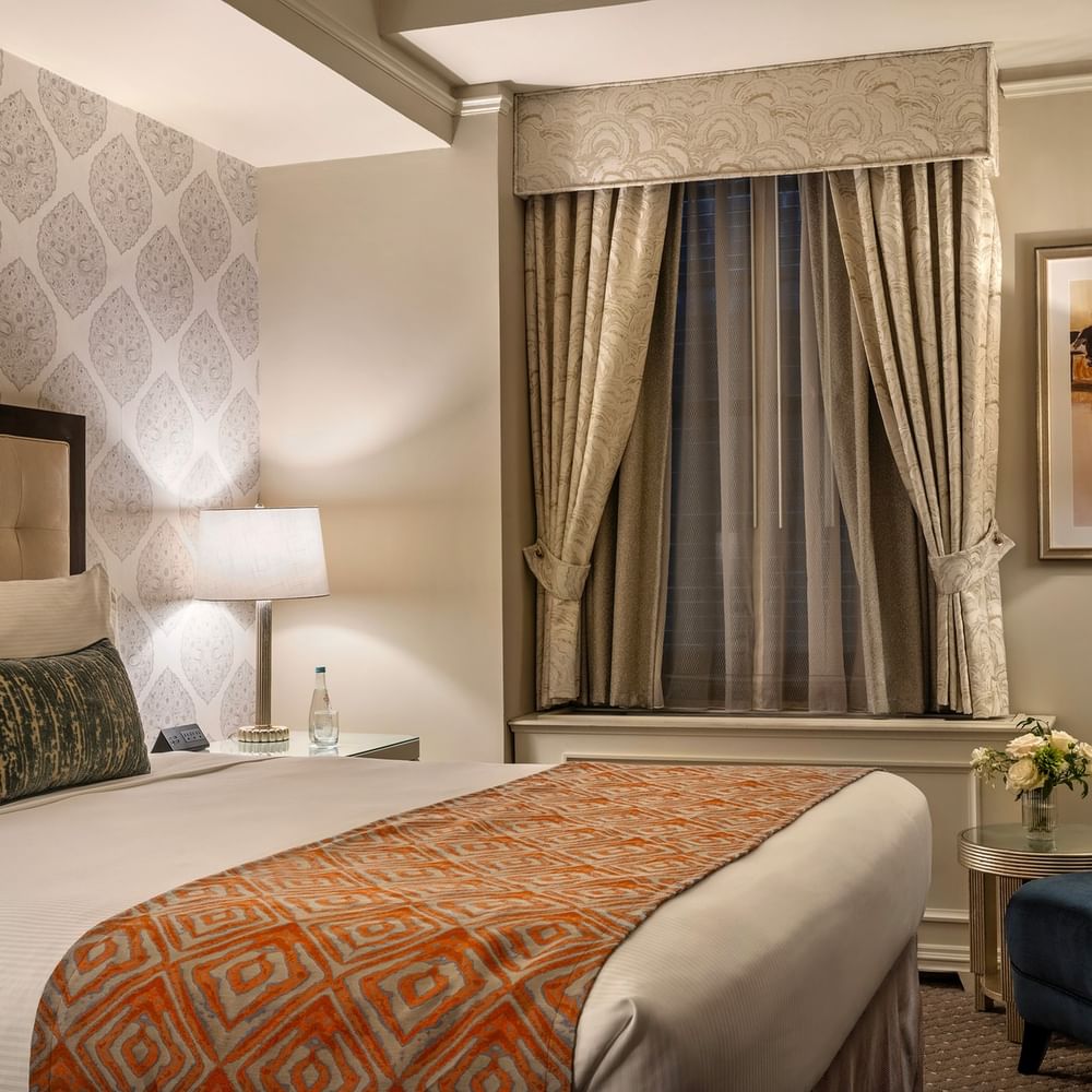 Bed with side table and couch near window in Premier Suite at Warwick New York