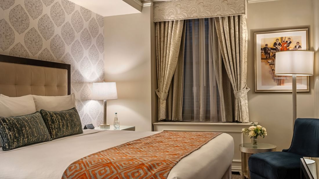 Bed with side table and couch near window in Premier Suite at Warwick New York