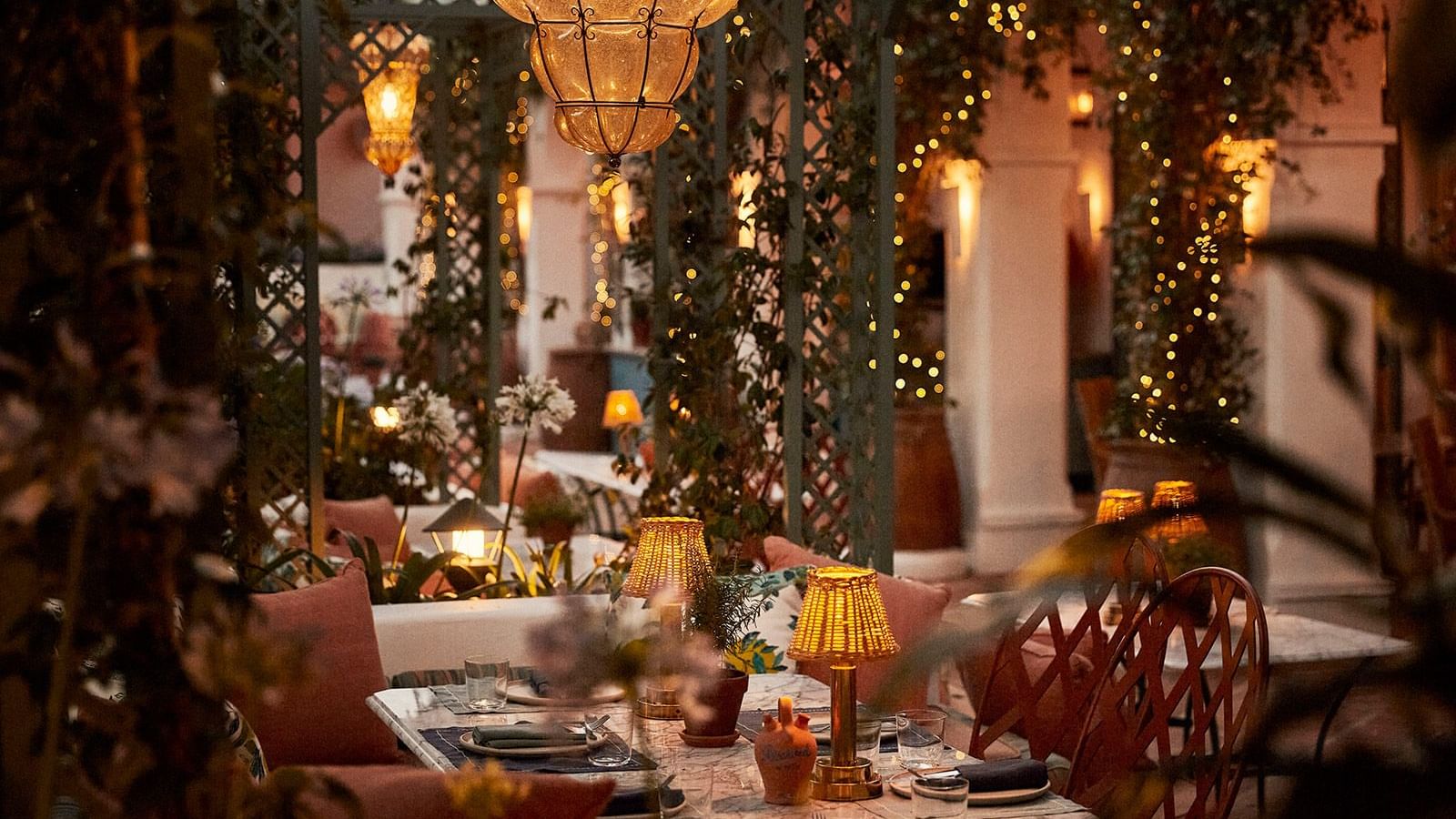 Marbella Club's outdoor dining table placed under a large amber glass chandelier and twinkling fairy lights at night