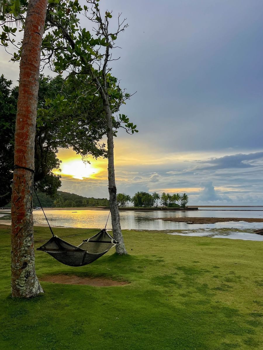 Hammock between trees on a grassy area overlooking a serene lake at The Naviti Resort Fiji.
