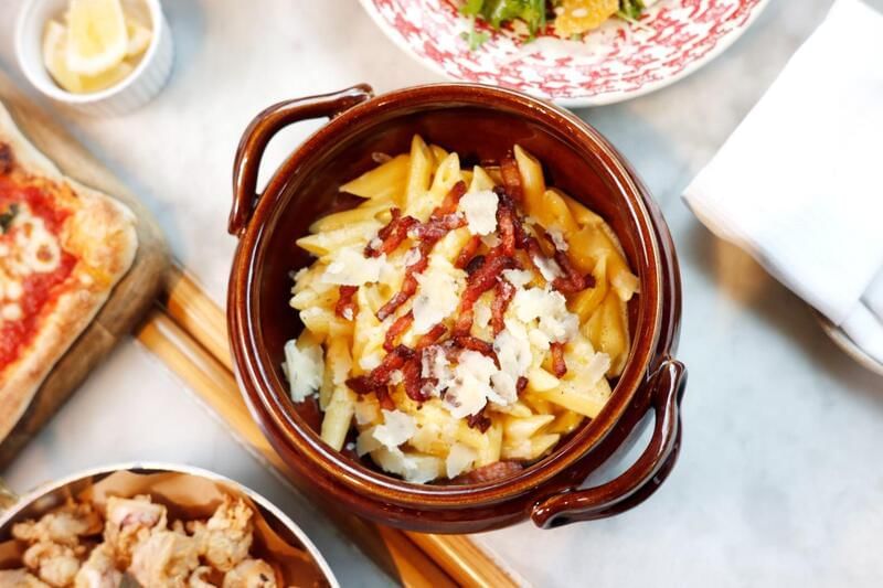 Dish of creamy penne pasta topped with crispy bacon and grated cheese at the family dinner in Park Hyatt Saigon