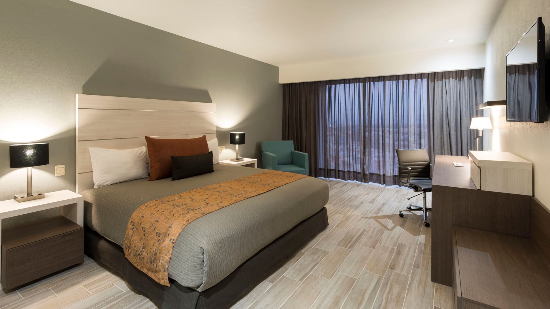 Work desk and cozy lounger by the bed in the King Deluxe Room with wooden floors at Real Inn San Luis Potosi
