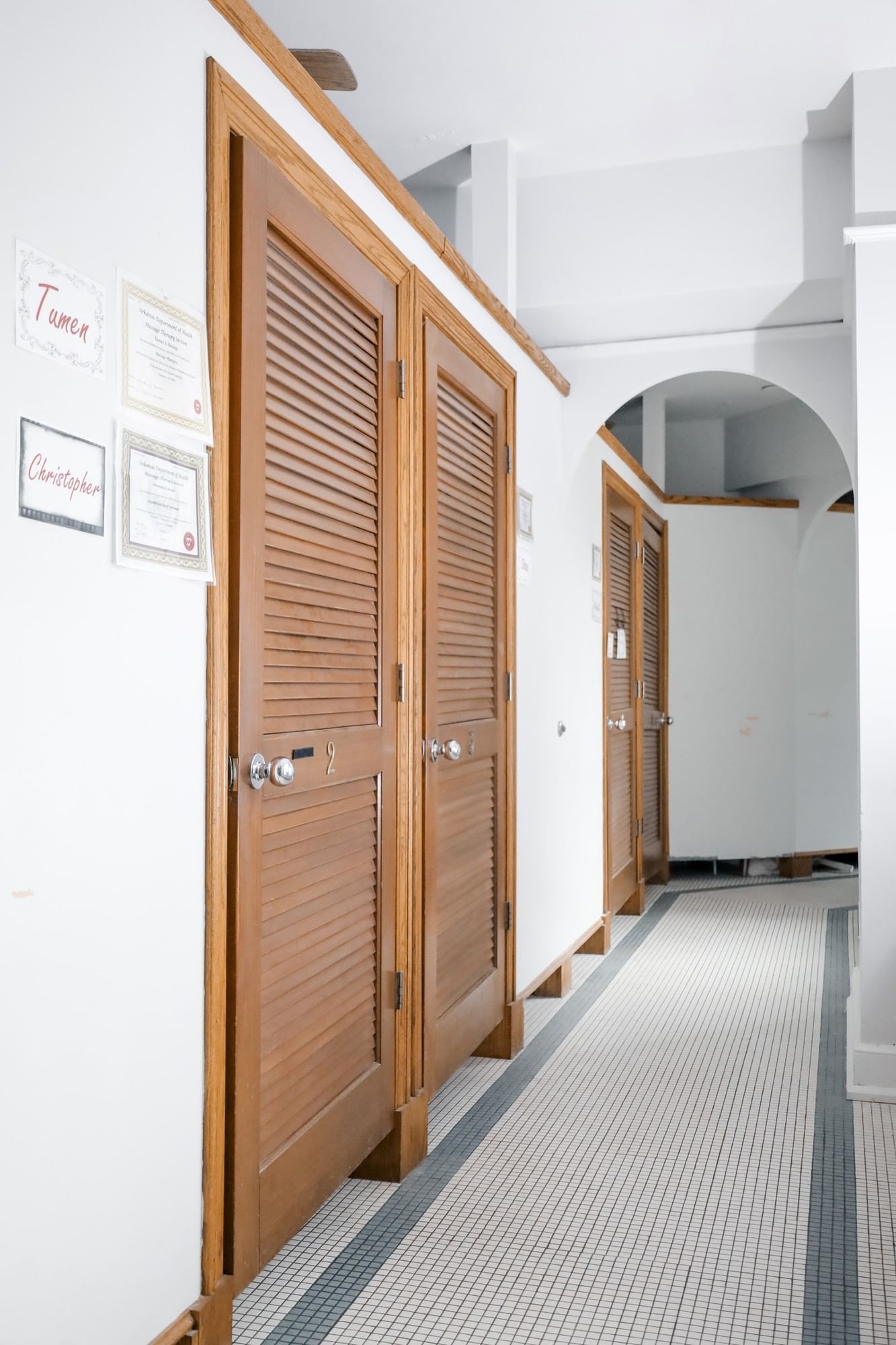 Wood slat doors by a white hallway under an arched ceiling in the spa area at Arlington Resort Hotel & Spa