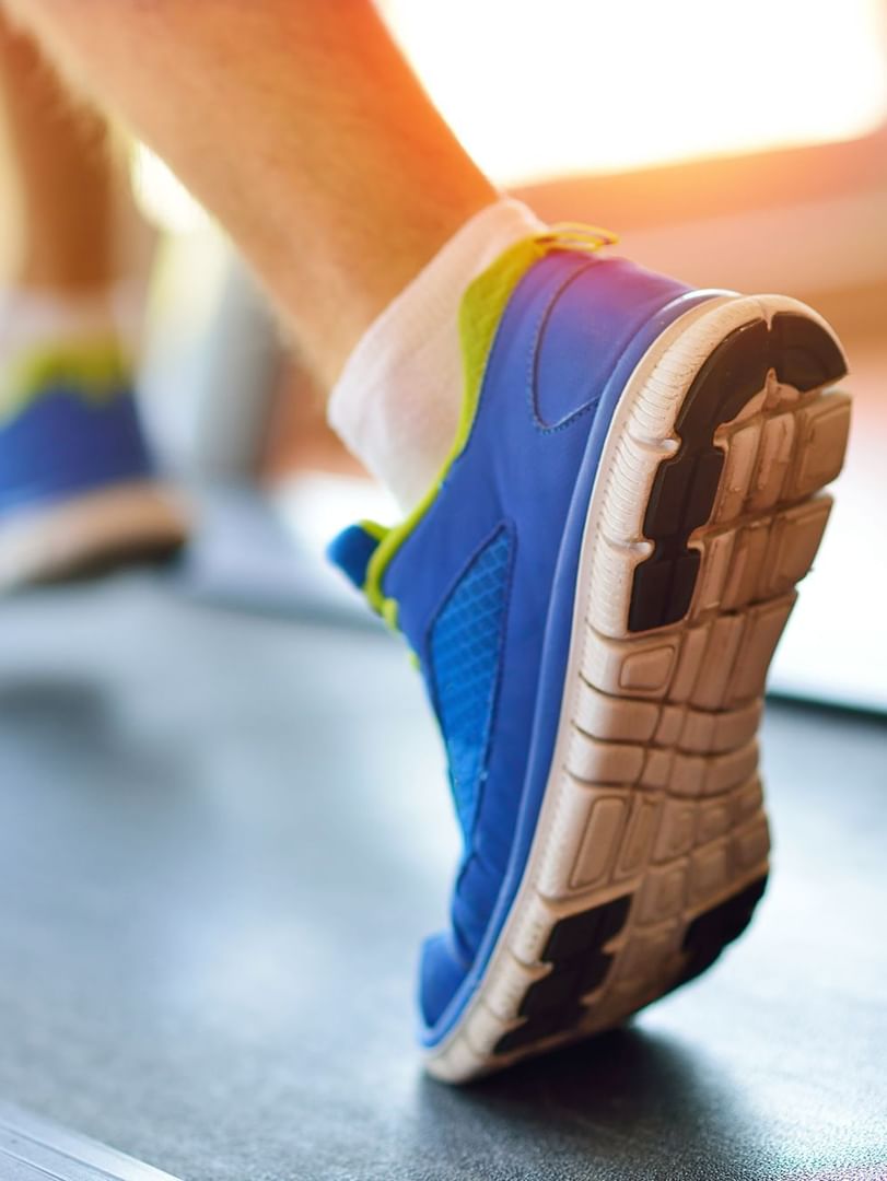Close-up of a Guest running on a treadmill by a large window at Warwick Melrose Dallas