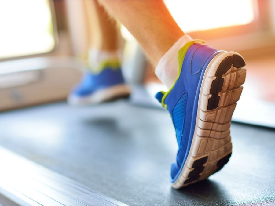 Close-up of a Guest running on a treadmill by a large window at Warwick Melrose Dallas