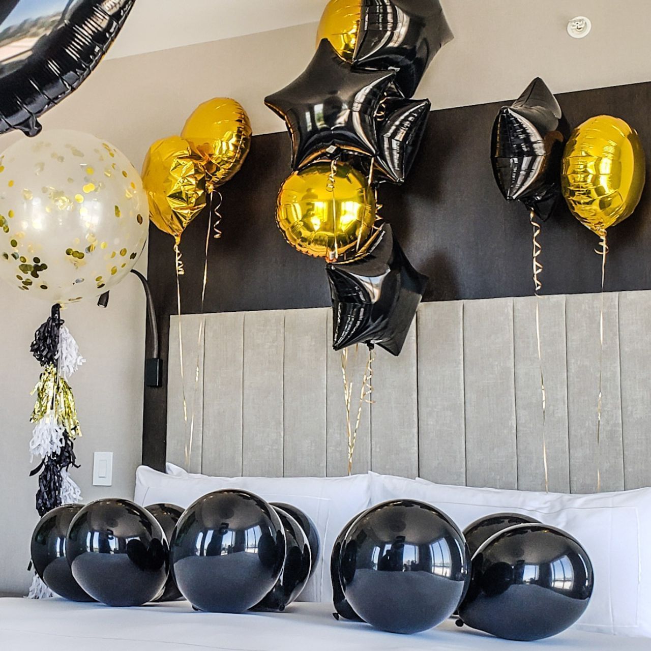 A hotel room with balloons and streamers decorating the bed and headboard.
