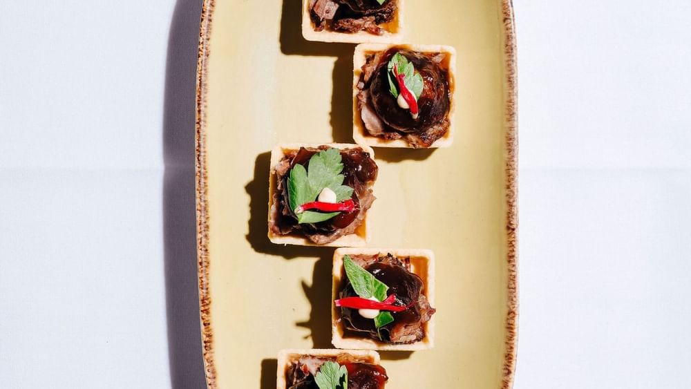 Five savory mini tartlets topped with herbs and red chili served in Parklands Room at Novotel Sydney Olympic Park