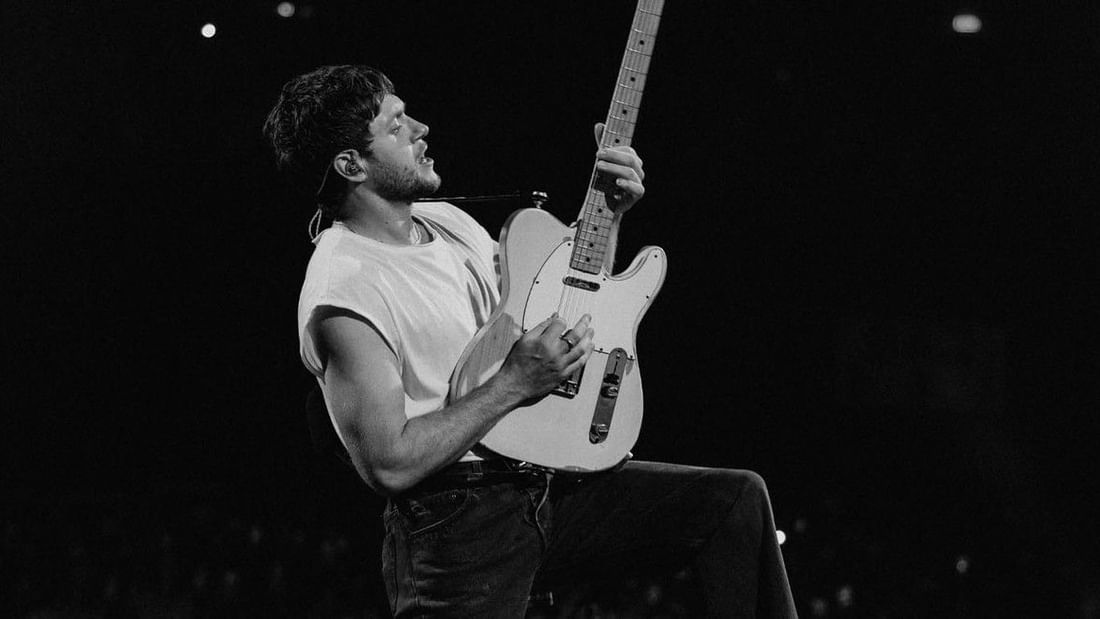 Black and white photo of a male musician playing an electric guitar on stage during a live performance