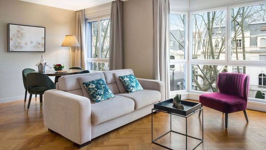 Dining table by the living area with plush seating and outdoor views in the Premium Suite at Warwick Reine Astrid - Lyon
