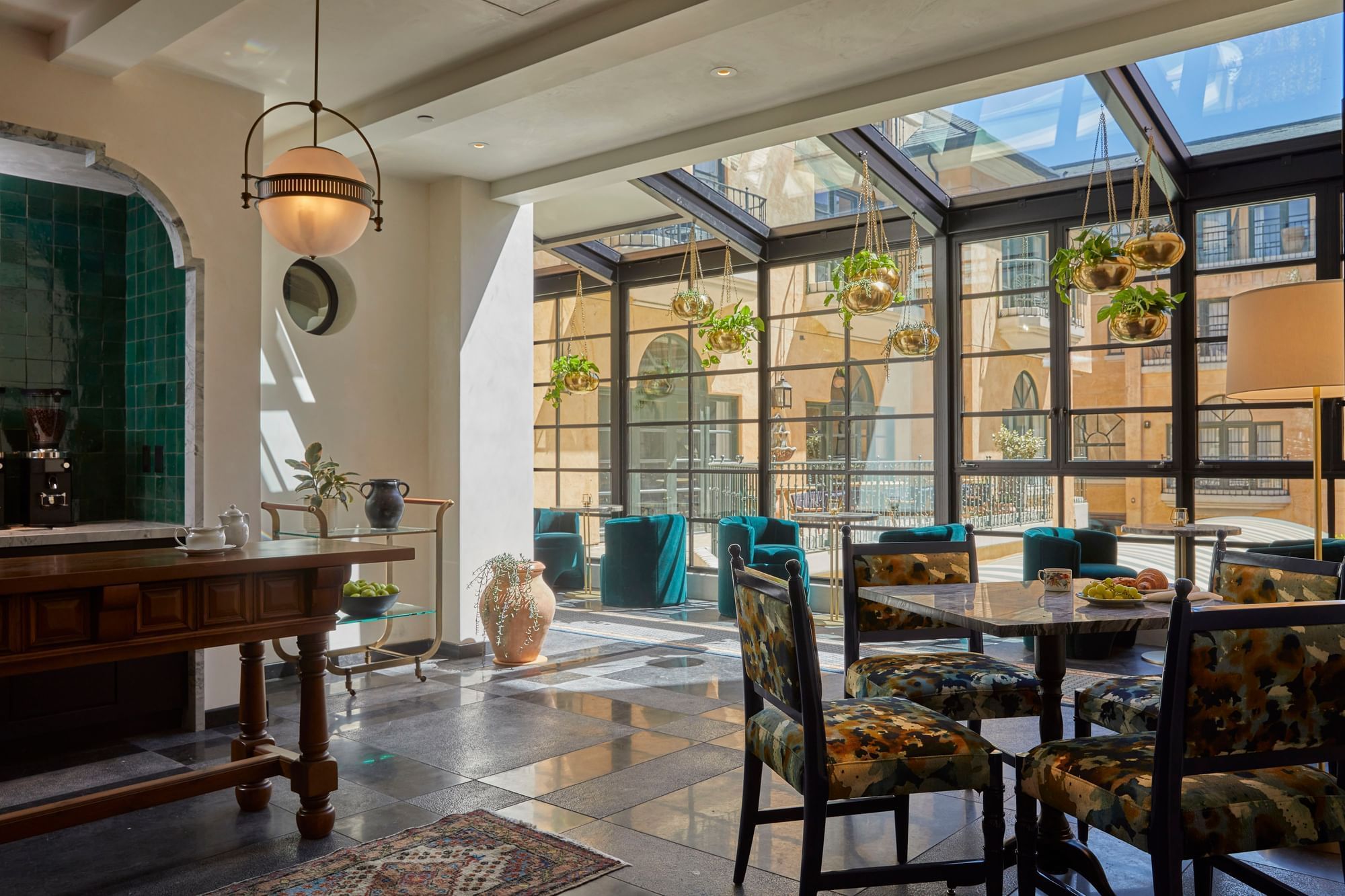 Sun-drenched common area with various seating and hanging plants at El Prado Hotel