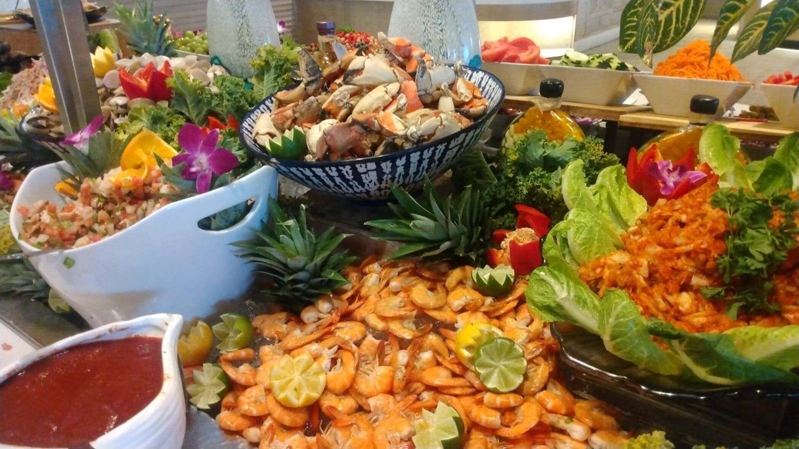 Assorted seafood dishes and garnishes on a buffet table, including shrimp, crabs, and tropical fruits.
