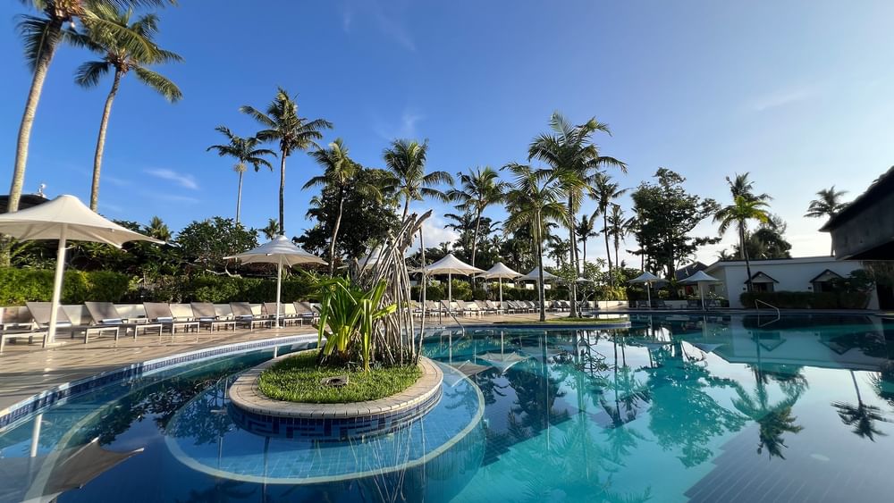 Pool and terrace beach area surrounded by palm trees at Warwick Le Lagon - Vanuatu in Efate.